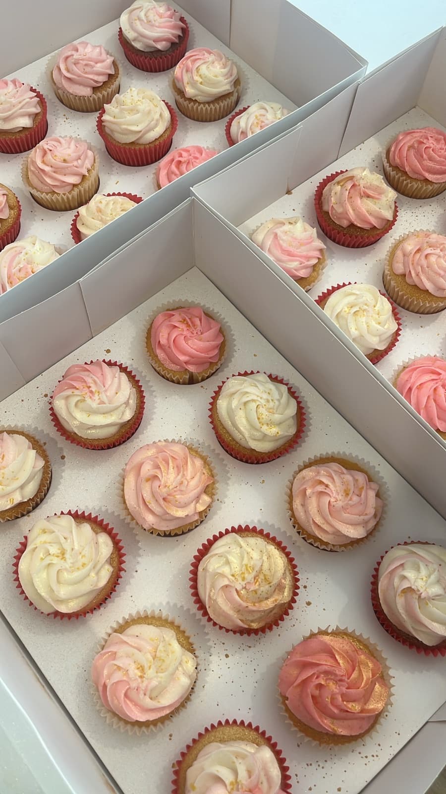Boxes of blush-pink and cream swirled cupcakes