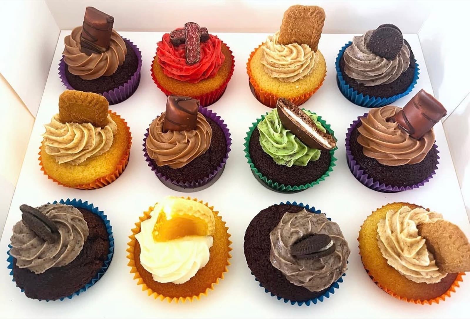 Assorted cupcakes in colourful liners with a variety of toppers