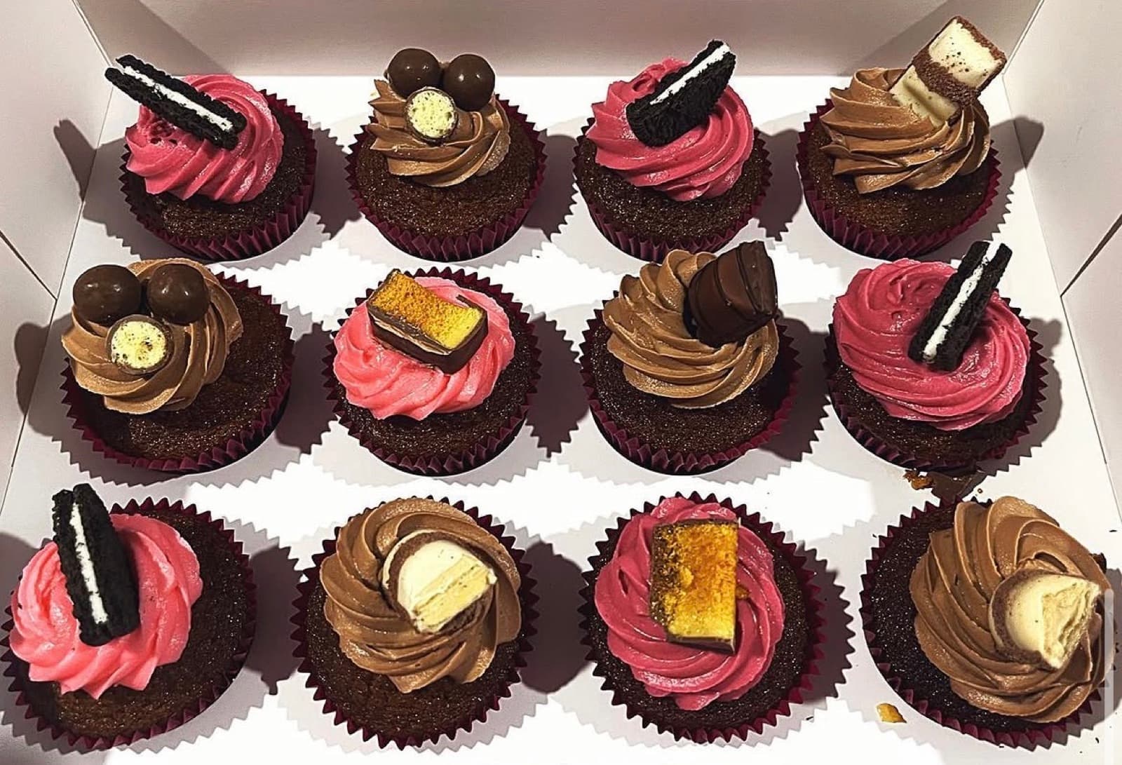 Chocolate cupcakes with pink and chocolate frosting and biscuit toppers