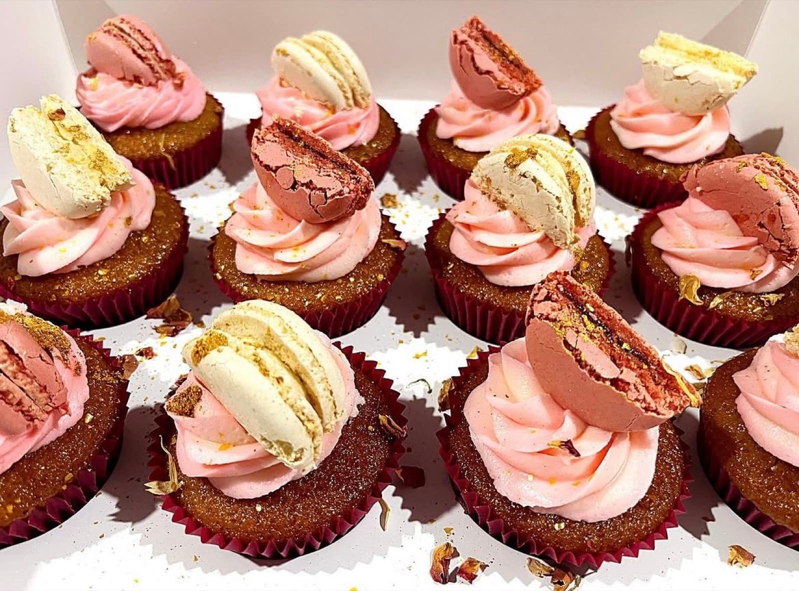 Cupcakes with pink buttercream swirls topped with macaron halves